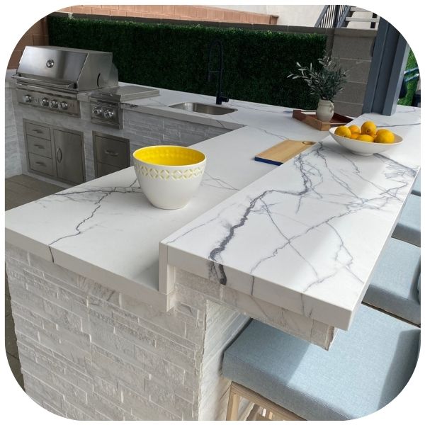 Beautiful outdoor kitchen with stunning light blue accent chairs and a heavily veined countertop